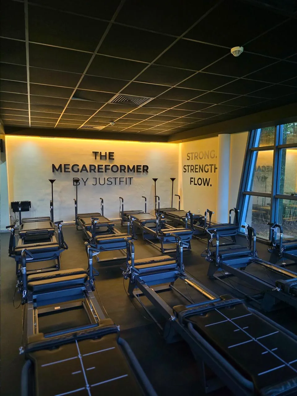 Studio Megaformer Just Fit : machines alignées face au mur lumineux